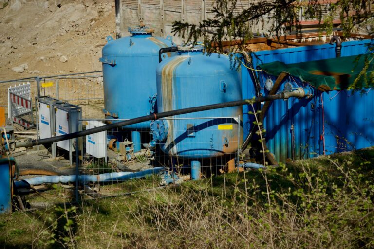 Outdoor industrial water filtration plant with large blue tanks under sunlight.