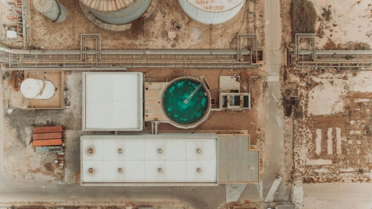 Top-down view of an industrial facility with prominent green water treatment tank.