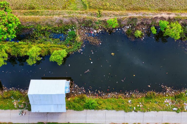 Drone shot of a polluted creek in Banten, Indonesia, showing water pollution and greenery.