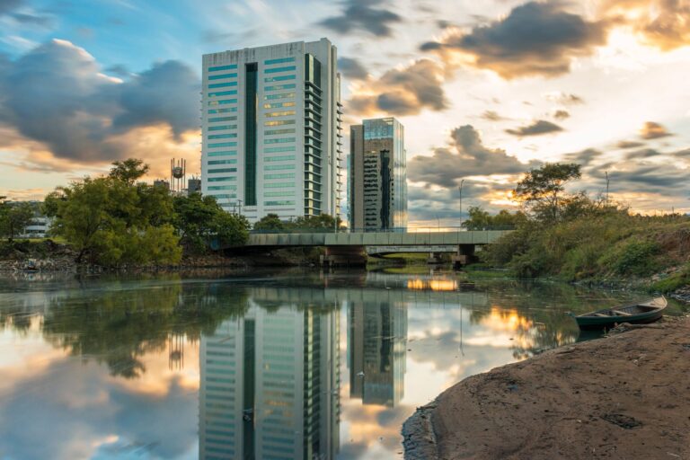 Captivating view of Porto Alegre's reflections in a river during sunset with clouds and modern architecture.